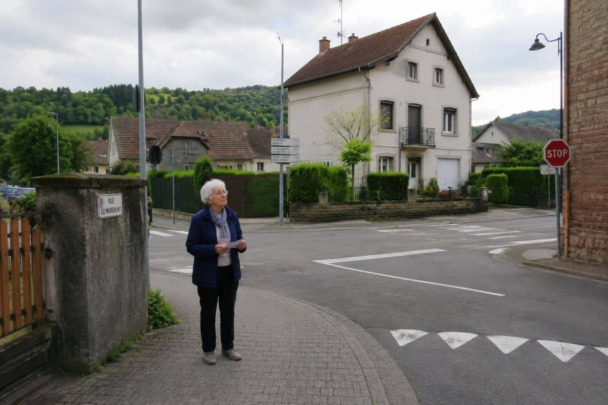 Elderly person standing at a quiet street corner, looking around as if trying to recognize the way home.